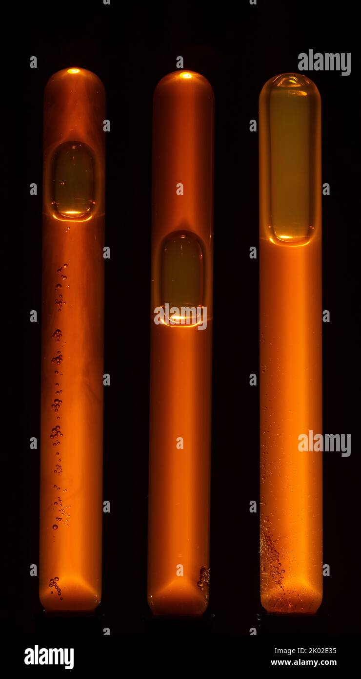 Lecitina di girasole liquida gialla viscosa con bolle in provetta trasparente su fondo scuro Foto Stock