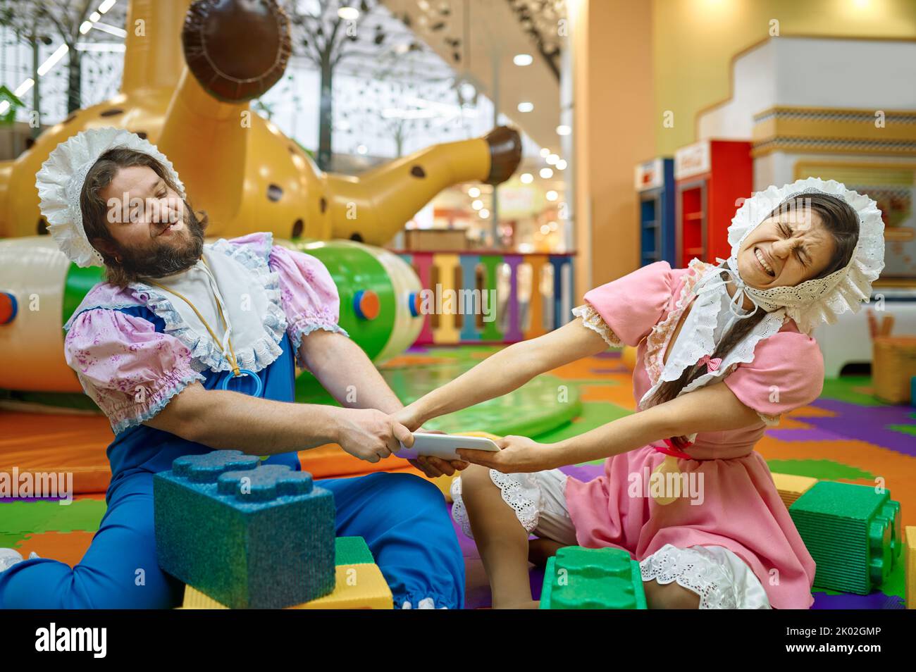 Divertente uomo e donna bambini che lottano per il tablet digitale Foto Stock