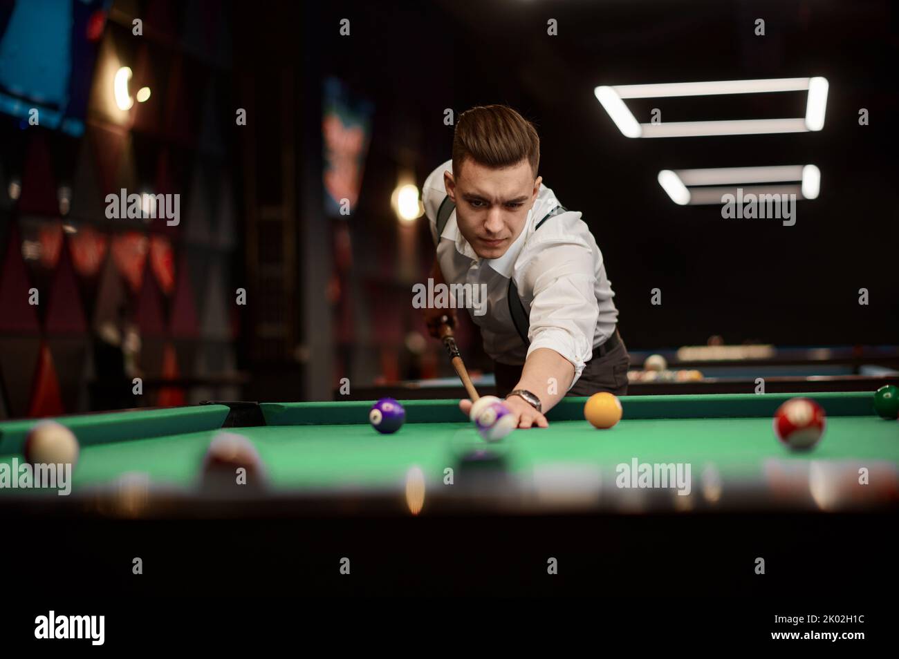 Ritratto di giovane uomo che prepara stecca da biliardo Foto Stock