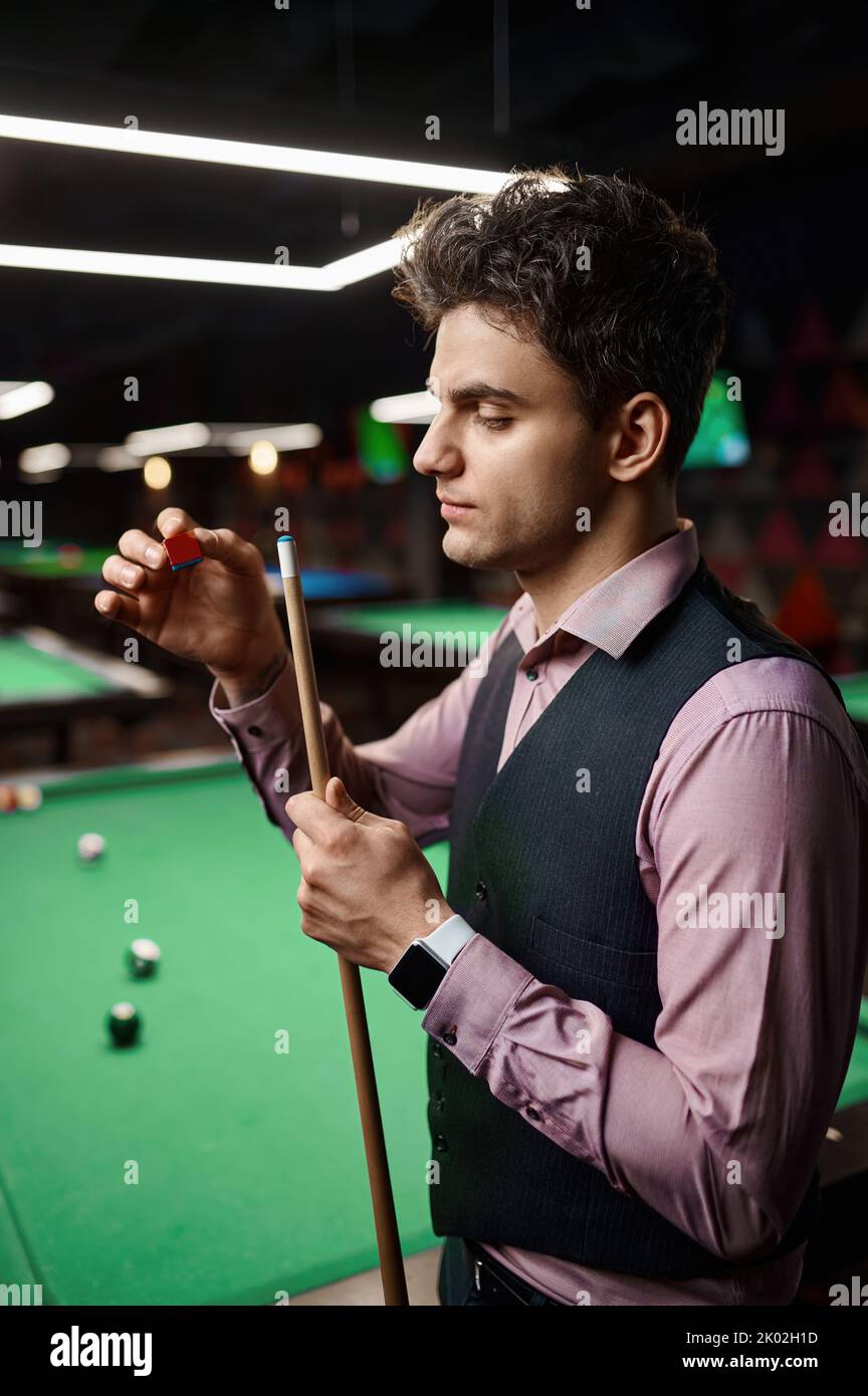 Closeup uomo giocatore biliardo rubbing cue Foto Stock