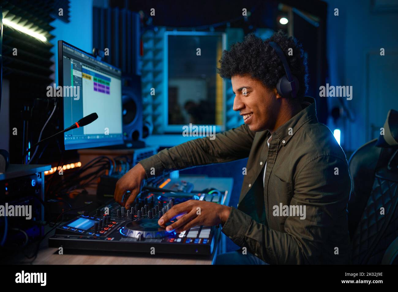 Giovane uomo che paga musica sul mixer audio nella stazione radio Foto Stock