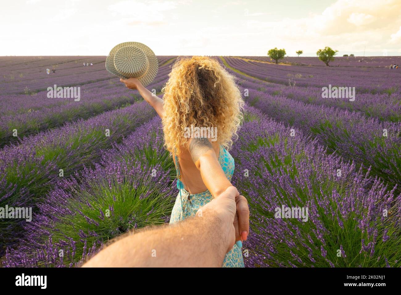 POV dell'uomo che tiene le mani della donna con il campo di lavanda bello sullo sfondo. Coppia felice nello stile di vita di viaggio godendo di una destinazione stupefacente in Europa. Amore e amicizia uomo e donna Foto Stock