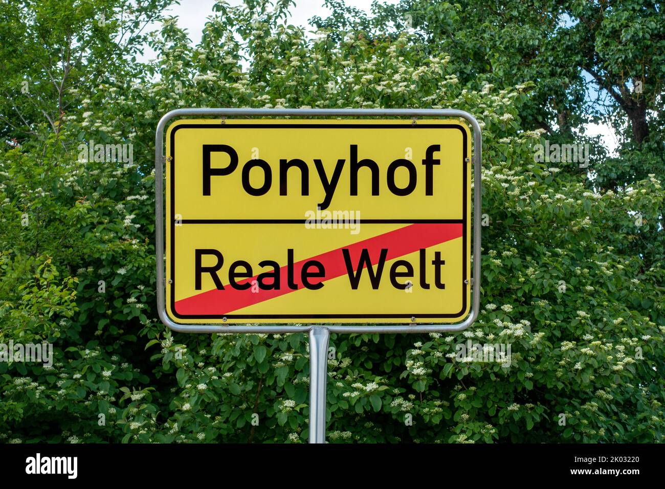 Nome luogo segno Ponyhof, qui finisce il mondo reale. Il cartello si trova di fronte alle scuderie presso le fattorie di Fauserhöhe vicino a Münsingen. Foto Stock