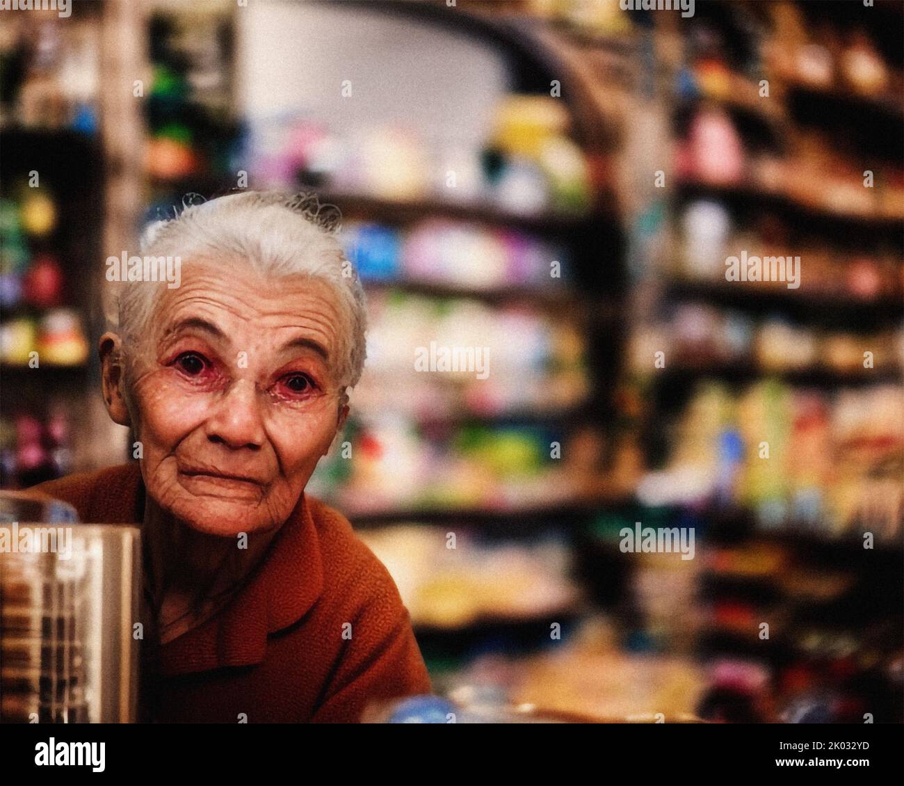 Una donna anziana dietro il bancone in un minimarket Foto Stock