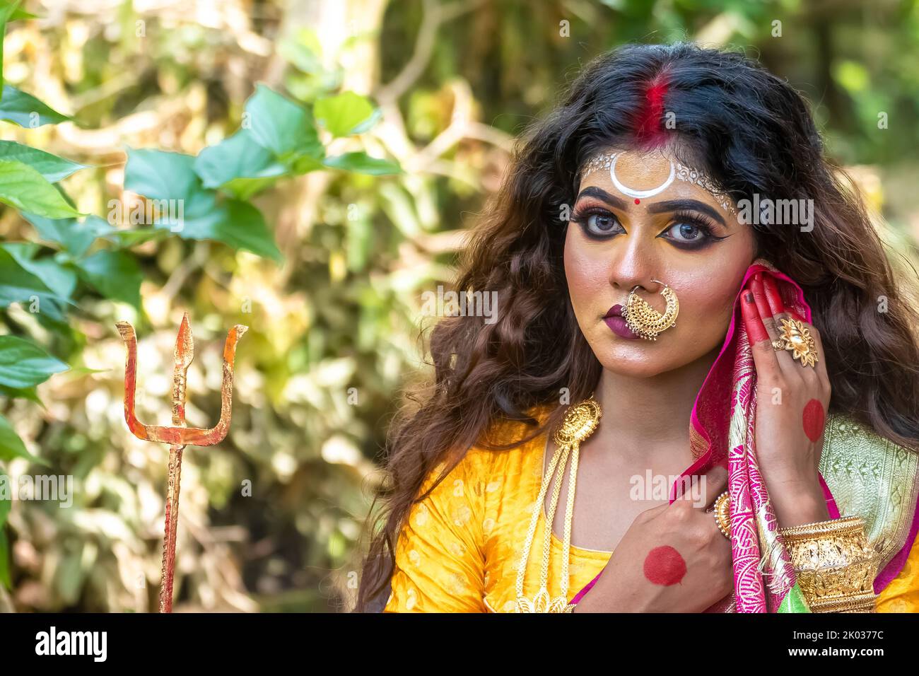 Concetto Agomoni sparare con capelli neri ragazza faccia indiana bruna con trucco perfetto e indossando gioielli con abito tradizionale come la dea . Foto Stock
