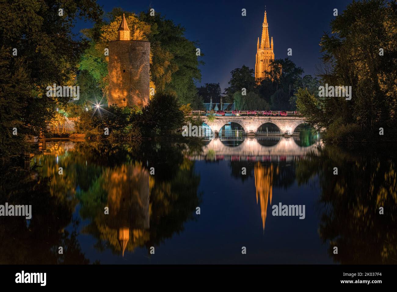 Minnewewater di notte, con il riflesso della Chiesa di nostra Signora, Minnewewater Bridge e una torre di difesa. Bruges, Fiandre, Belgio. Foto Stock