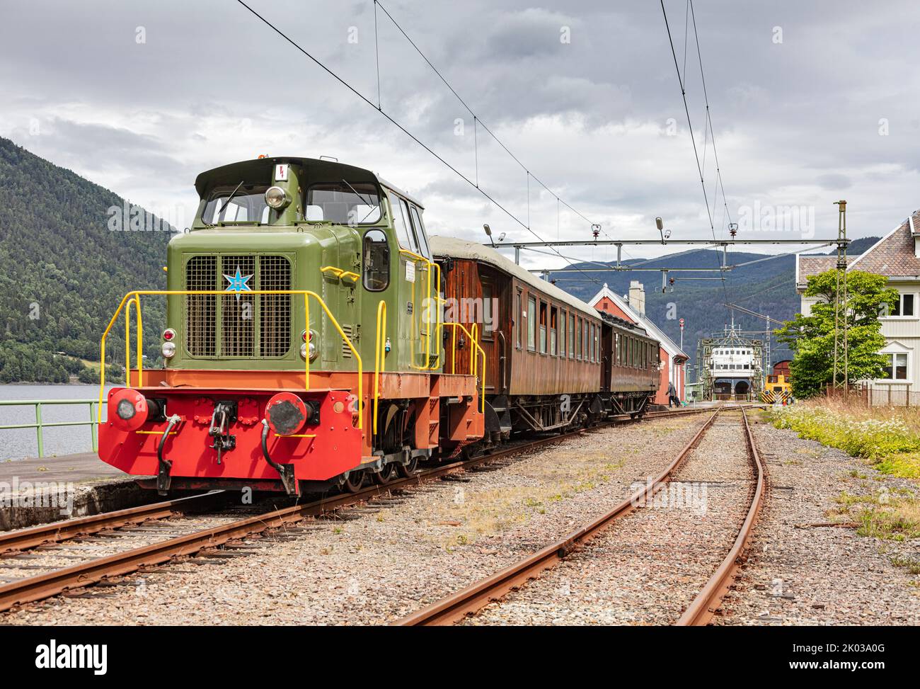 Norvegia, Vestfold og Telemark, Rjukan, Mæl, stazione ferroviaria, treno in piedi sulla piattaforma, locomotiva diesel, vagoni in legno di teak, traghetto ferroviario Storgut (sfondo) Foto Stock