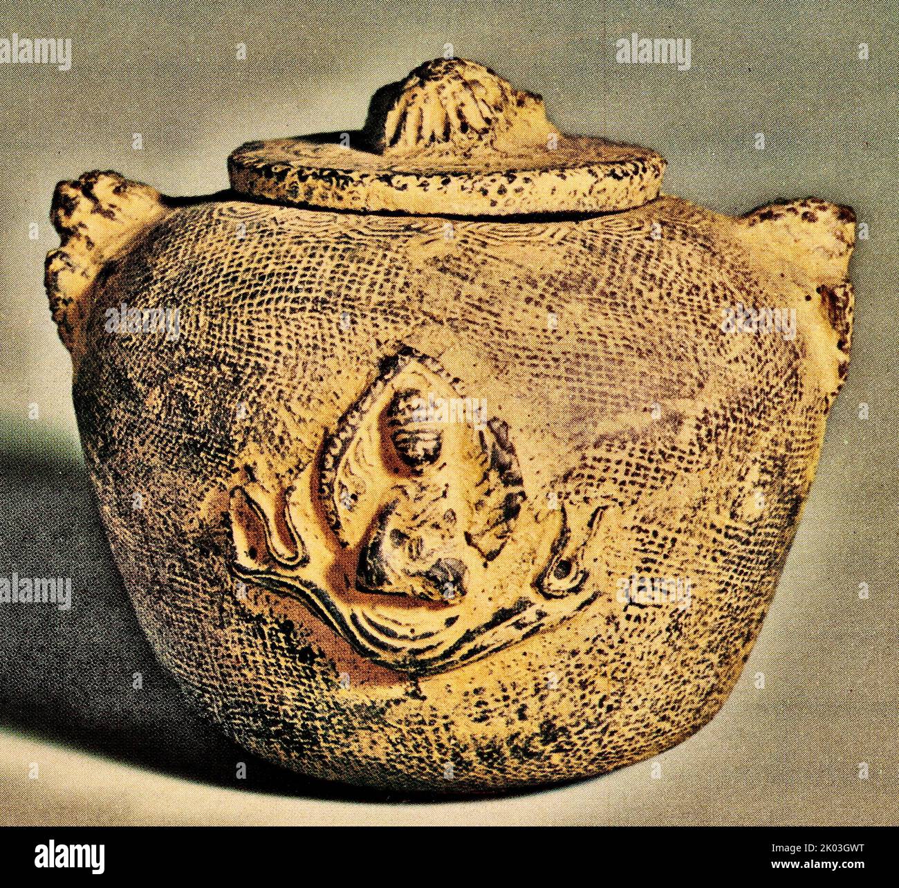 Vasetto Han Dynasty ricoperto da motivi a reticolo e nuvole sulla superficie piana intorno al bordo della bocca. Ci sono due manopole a forma di animali che si siedono sulle spalle, una manopola a forma simile piantata sul coperchio. Su un lato del piccolo vaso si trova Buddha e un drago. Sul lato opposto è iscritta la scritta 'Made in the Third year of Chien Chao (36 a.C.)' in stile sigillo. Il vaso esemplifica il sostegno di Han per la semplicità dei funerali. Foto Stock