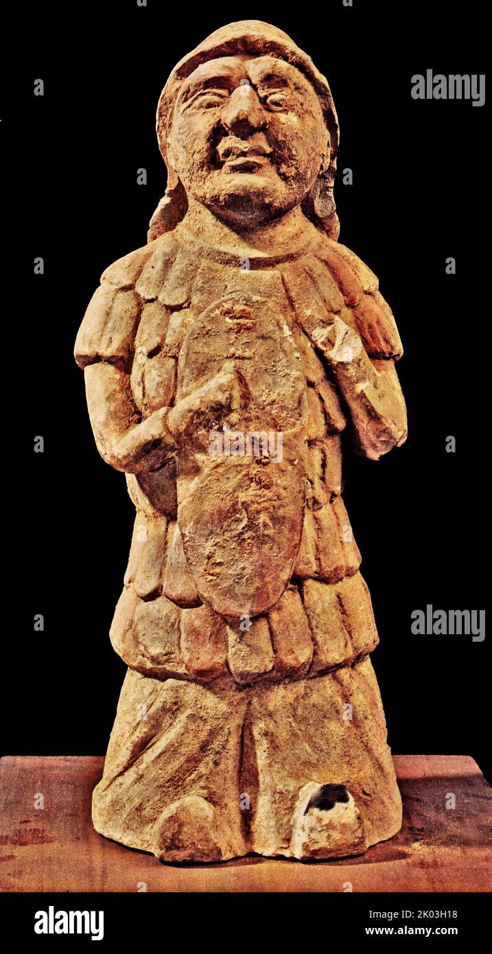 Figurine della dinastia Han di ufficiali militari, che indossano caschi, senza protezione e spalle posteriori, e che indossano armatura, che è fatta di molti pezzi di armatura. Tiene uno scudo nella mano destra sul petto, la mano sinistra è disabile, e indossa pantaloni a tubo grande, rivelando leggermente la punta. Le figurine hanno una testa grande, faccia rotonda, occhi gonfie, naso alto, bocca larga, E assomiglia al popolo Hu. Il terreno è scuro, con colori rossi e bianchi, molti dei quali sono caduti, e il corpo è ricoperto di loess. Foto Stock