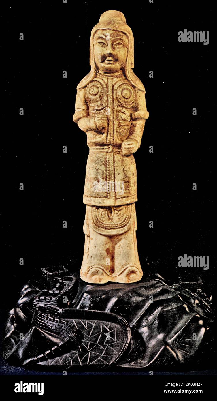 Sui Dynasty Figurine indossa un casco, che ha anche un panno sotto per fornire una copertura supplementare. L'armatura di questo ufficiale copre le ginocchia. C'è un buco in una delle mani aggrappate per tenere un'arma persa. Sebbene originariamente dipinte in rosso e nero e smaltate in giallo chiaro, la maggior parte dei pigmenti sono stati sostituiti da incrostazioni di terra. Foto Stock