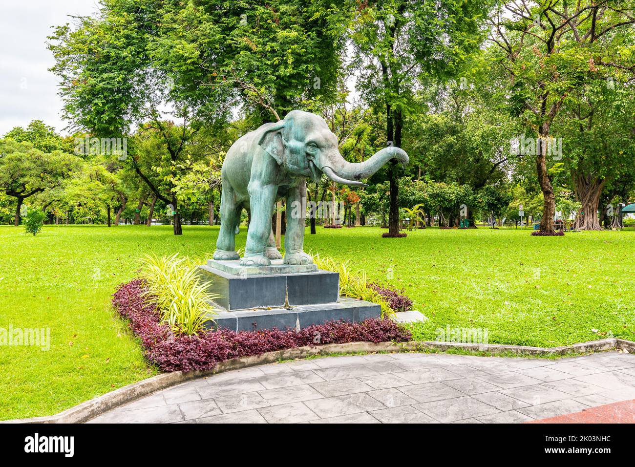 Statua dell'elefante nel parco pubblico di Bangkok, Thailandia. La statua è posta sulla scrivania con fiori vicino. L'elefante è il simbolo religioso del buddismo in Tailandese Foto Stock