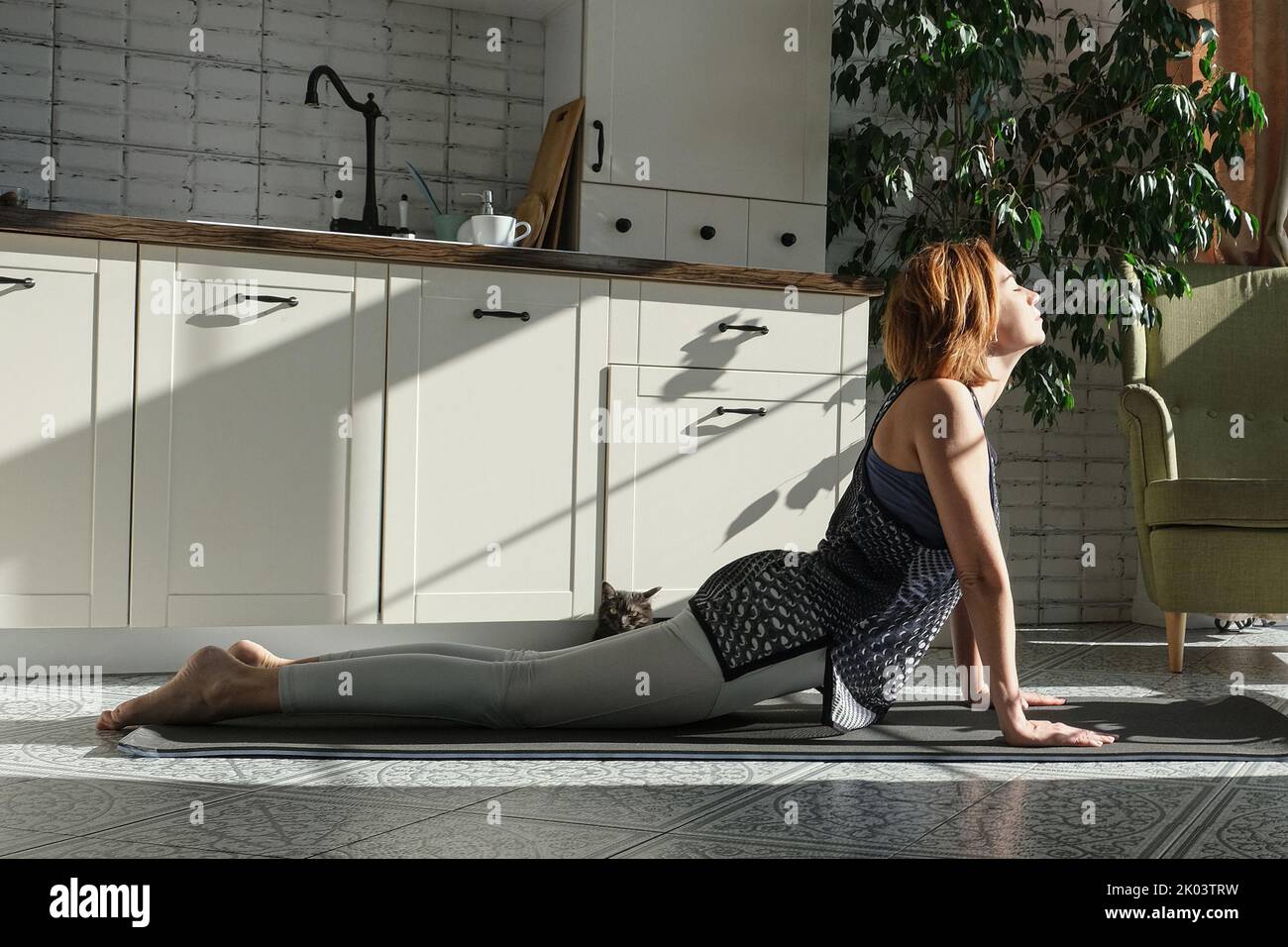 Donna di mezza età che pratica la meditazione a casa, calma anziana signora di mezza età in lotus posa fare yoga per l'equilibrio mentale respirare in cucina Foto Stock
