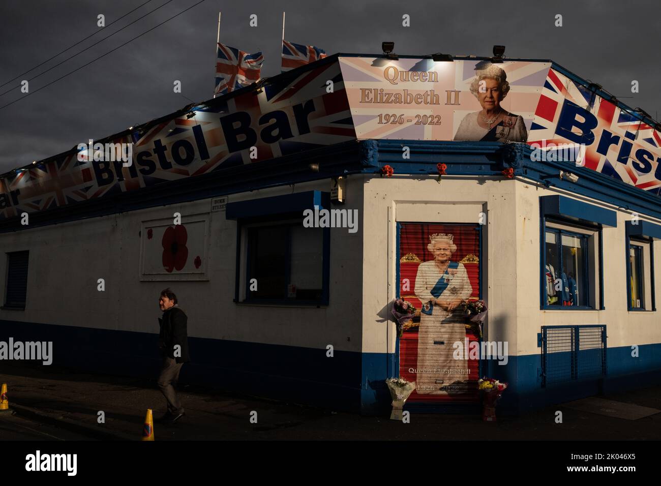 Glasgow, Scozia, 9 settembre 2022. Il Bristol Bar, uno dei preferiti dai sostenitori dell'Unionist e del Rangers FC, mostra un ritratto della Regina Elisabetta II e vola bandiere a metà albero, come segno di rispetto per sua Maestà, che è morta a 96 anni, a Glasgow, Scozia, il 9 settembre 2022. Photo credit: Jeremy Sutton-Hibbert/ Alamy Live news. Foto Stock