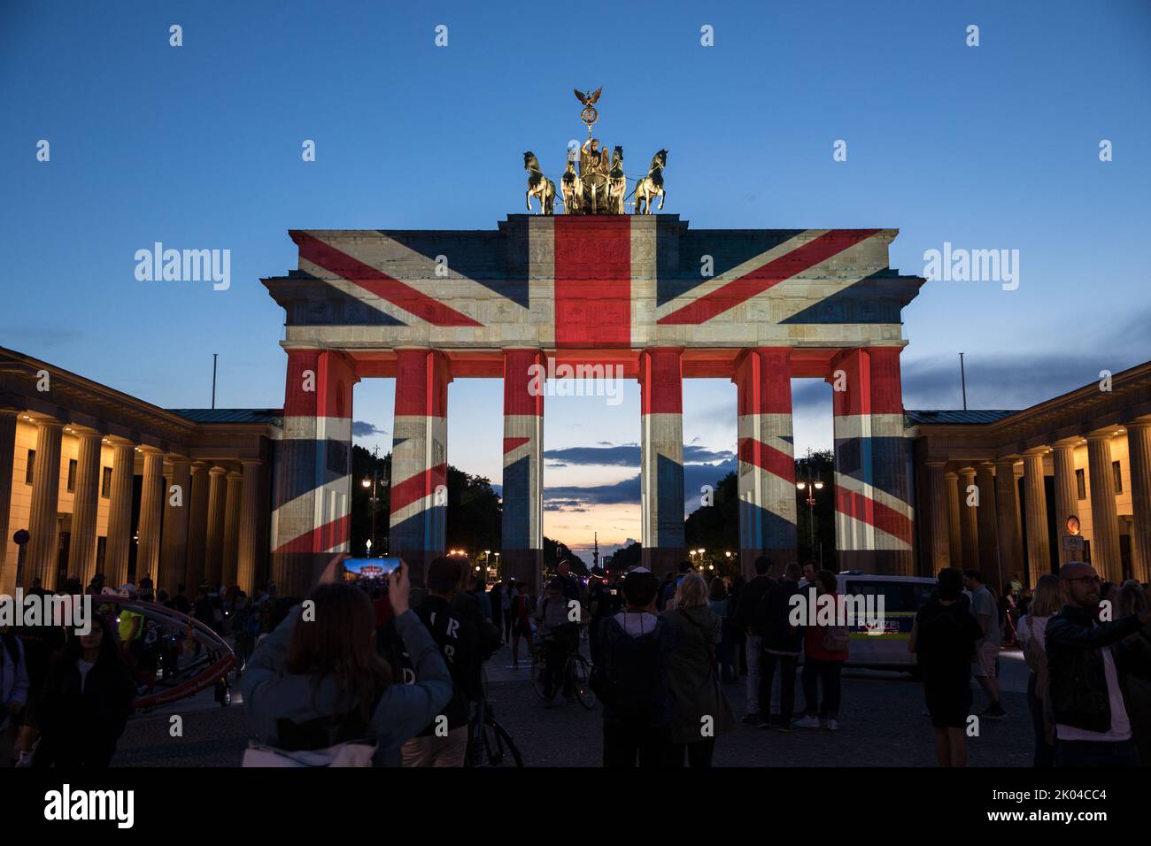 Berlino, Germania. 9th Set, 2022. Nella capitale tedesca di Berlino, la porta di Brandeburgo è stata illuminata con la bandiera dell'Unione la sera del 9 settembre 2022, in lutto della regina Elisabetta II Molte persone si sono riunite a Pariser Platz per esprimere la loro solidarietà. La regina Elisabetta II aveva guidato attraverso la porta di Brandeburgo nel 2015 con il principe Filippo nella sua limousine dopo aver detto Arrivederci a Pariser Platz. La regina Elisabetta II arrivò per la prima volta a Berlino, che era ancora divisa all'epoca, nel 1965, come primo capo di stato britannico dalla seconda guerra mondiale, dove fu accolta da un pubblico di almeno uno Foto Stock