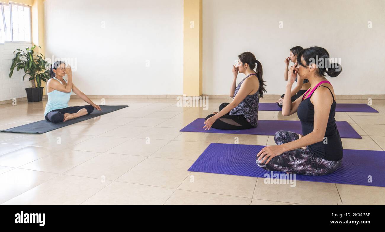 Un istruttore di yoga conduce una lezione alternativa di respirazione narice ad un gruppo di donne in una sala esercizi Foto Stock