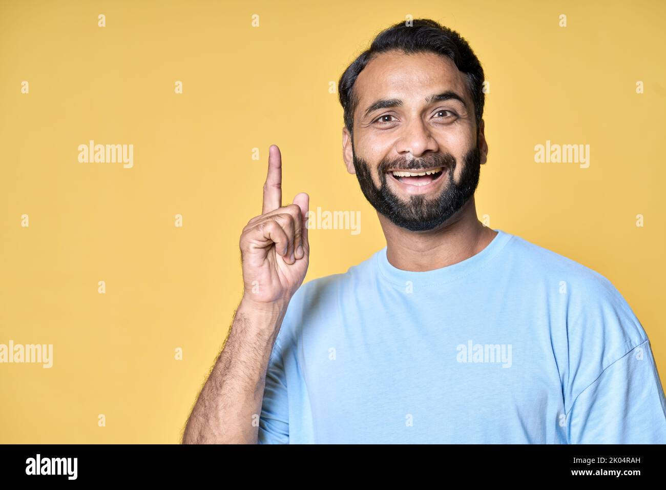 Felice eccitato indiano uomo puntando dito ha ottenuto nuova grande idea isolato sul giallo. Foto Stock
