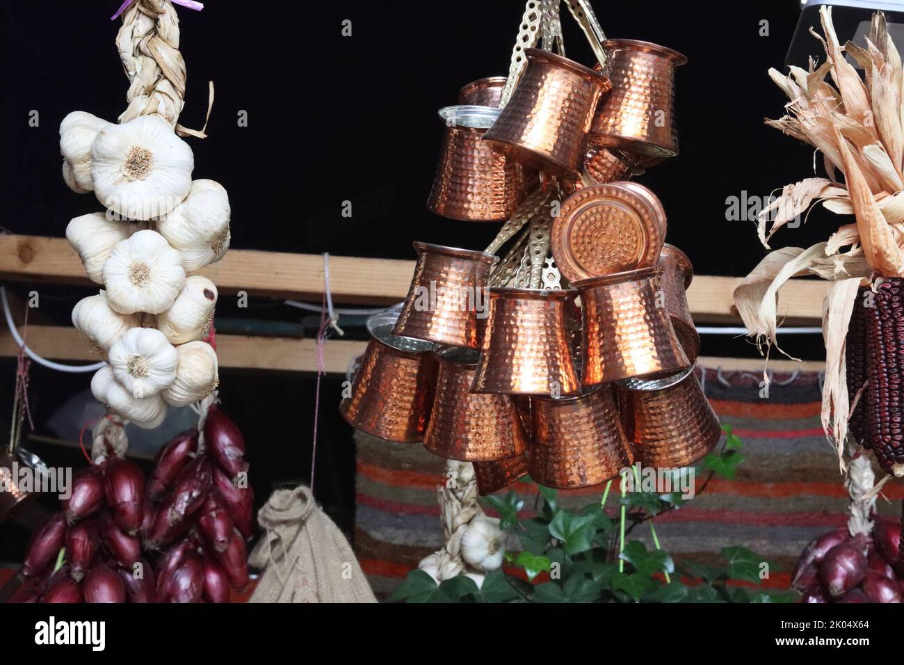 Mazzo di caffè turco in bronzo cooper goffrato e trecce di aglio bianco e cipolle rosse appese nel mercato orientale di Heildeberg. Clos Foto Stock