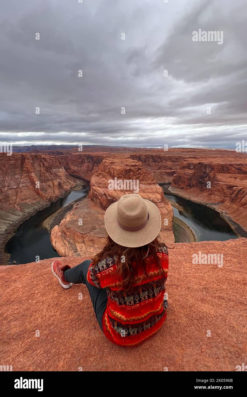 Donna seduta sul bordo con vista a ferro di cavallo curva, vista dal retro Foto Stock