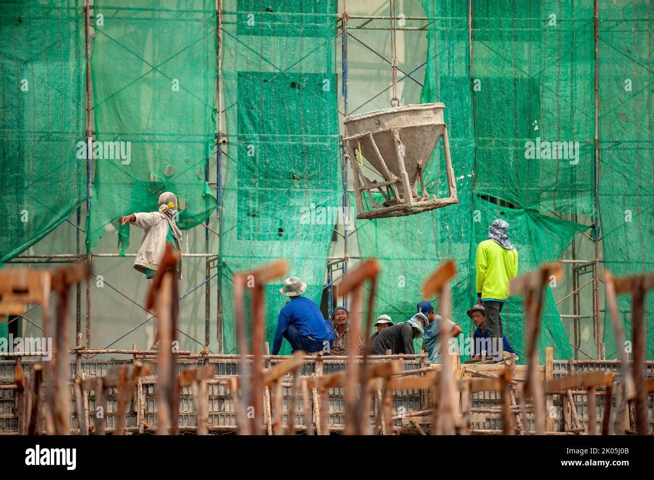 Bangkok, Thailandia 5 settembre 2015: Benna in cemento issata da gru consegnata a un team di operai edili sottostante. Foto Stock