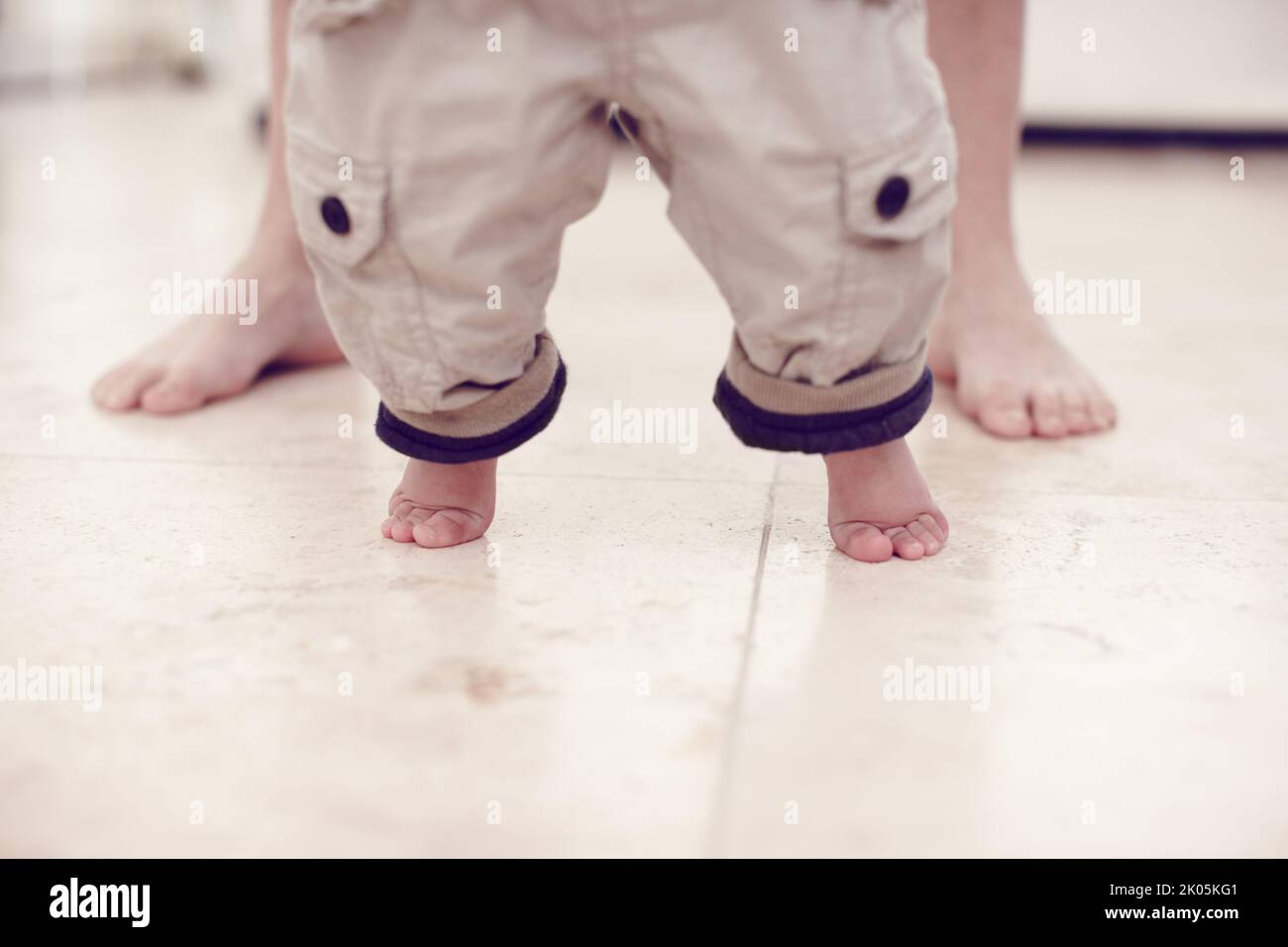 Prendendo quei primi passi tentativi... vista ritagliata di un bambino che impara a camminare. Foto Stock