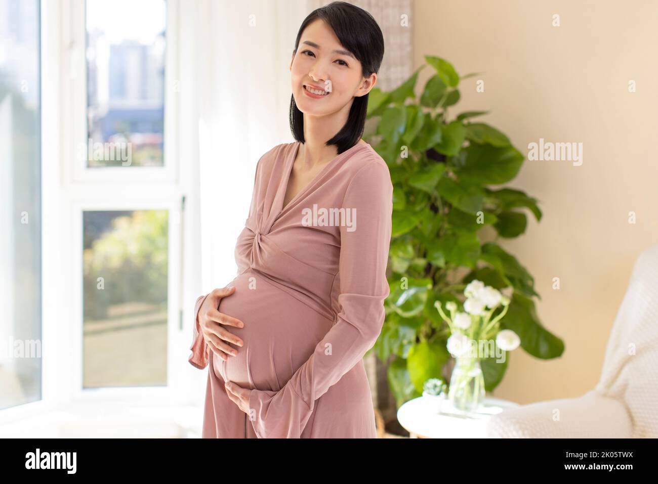 Cinese Allegra donna incinta in un momento di relax a casa Foto Stock