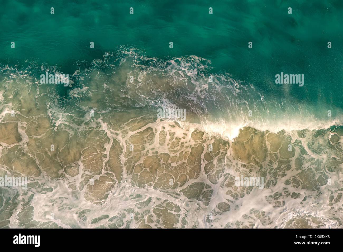 Vista dall'alto dei modelli di schiuma bianca dall'impatto delle onde oceaniche sulle rocce costiere. Sudafrica Foto Stock