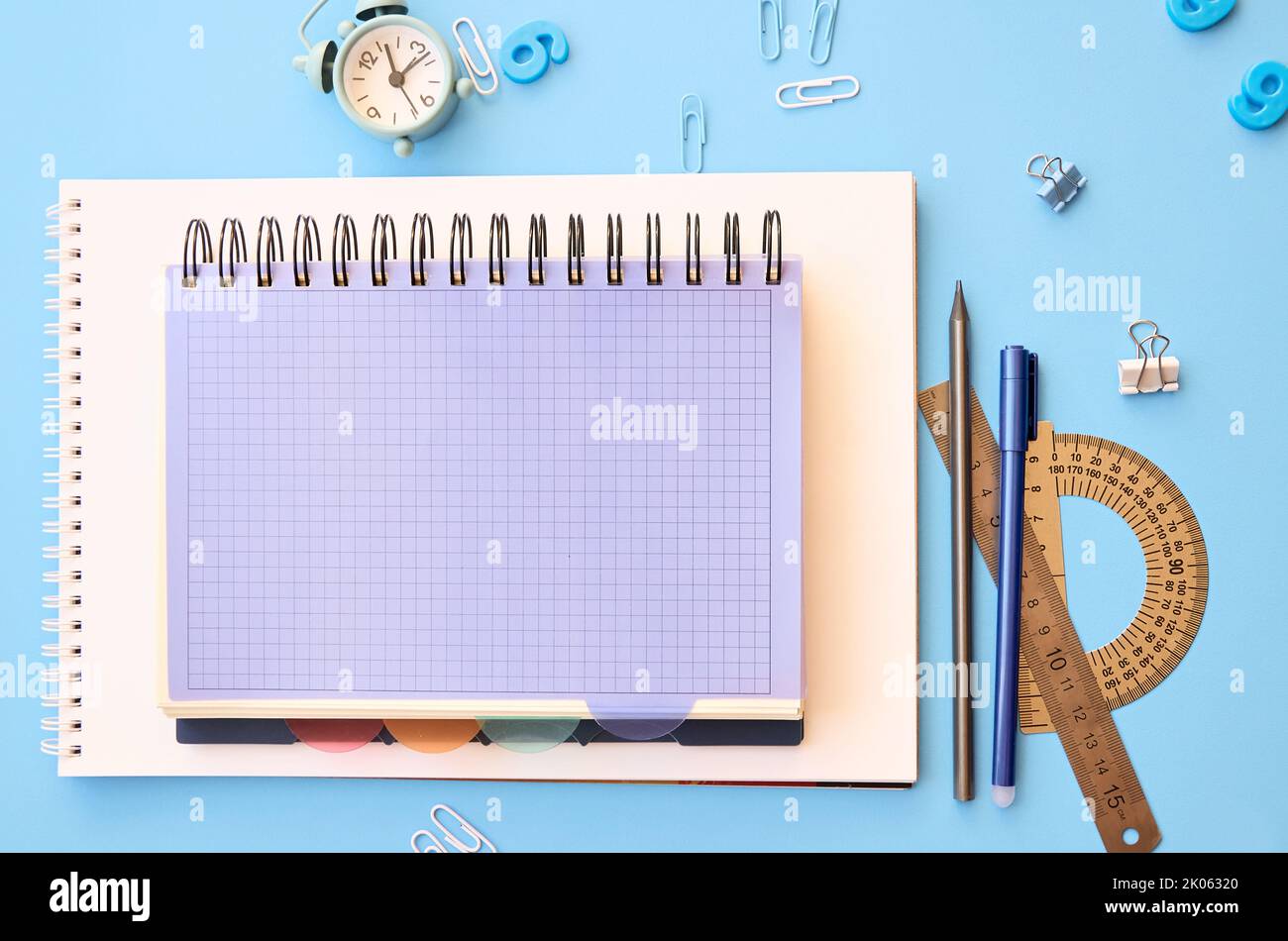 Accessori per la scuola su tavolo blu, piano di sfondo scrivania. Foto Stock