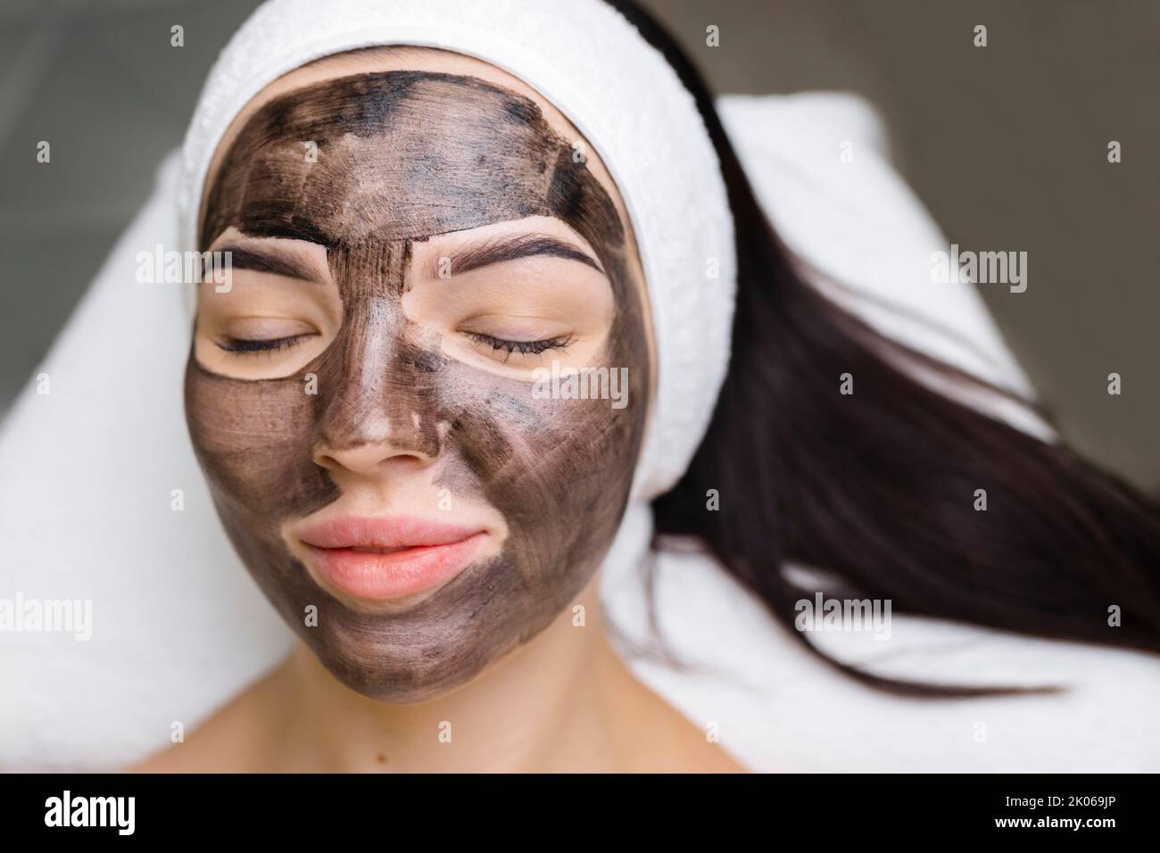 cosmetologo applicazione maschera nera sul viso bella donna indossare guanti neri, donna splendida in spa che hanno le procedure facciali Foto Stock