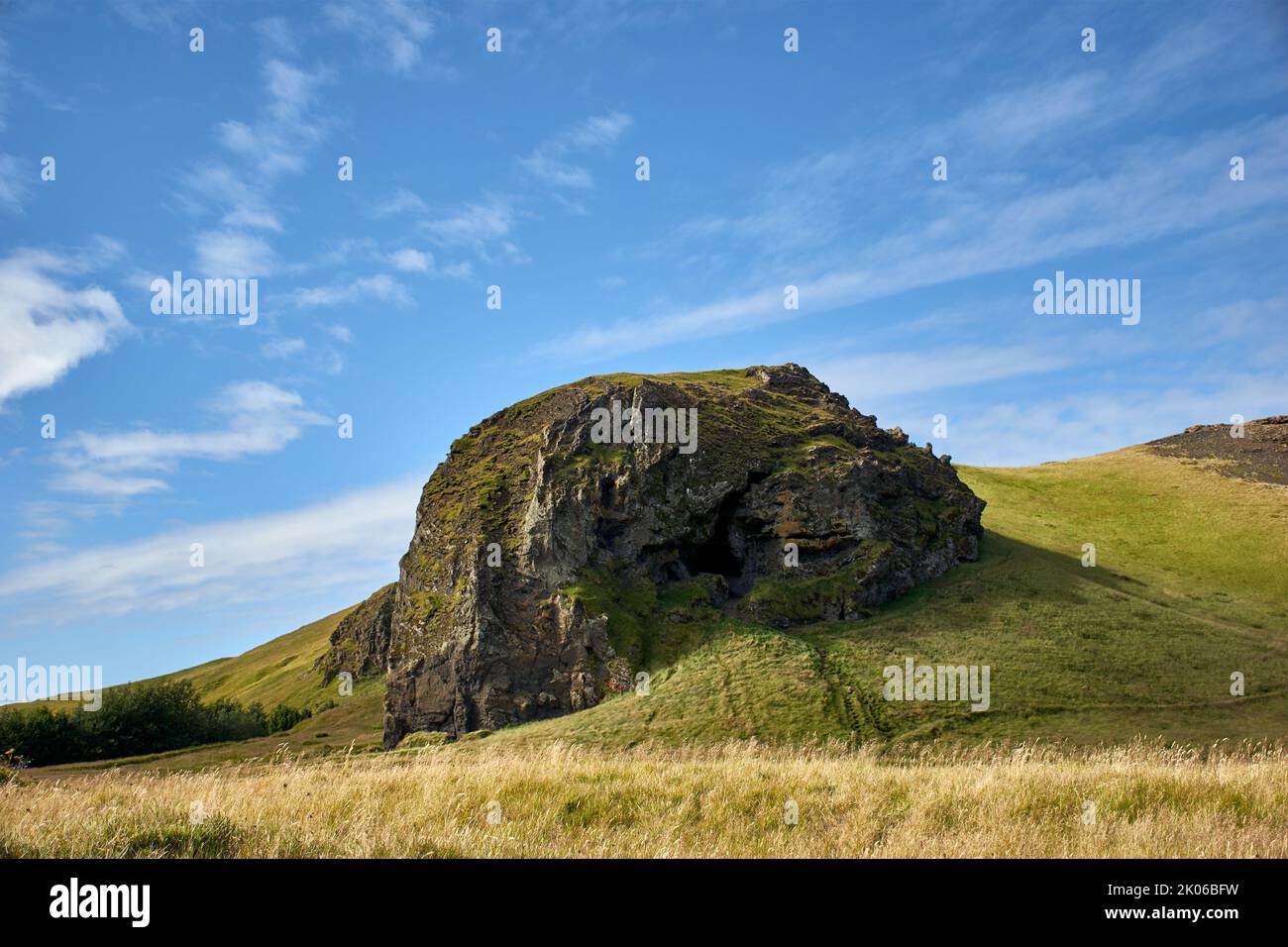 Rock in verde paesaggio e cielo blu vicino al vulcano Eyjafjallajökull, Sud Islanda. Foto Stock