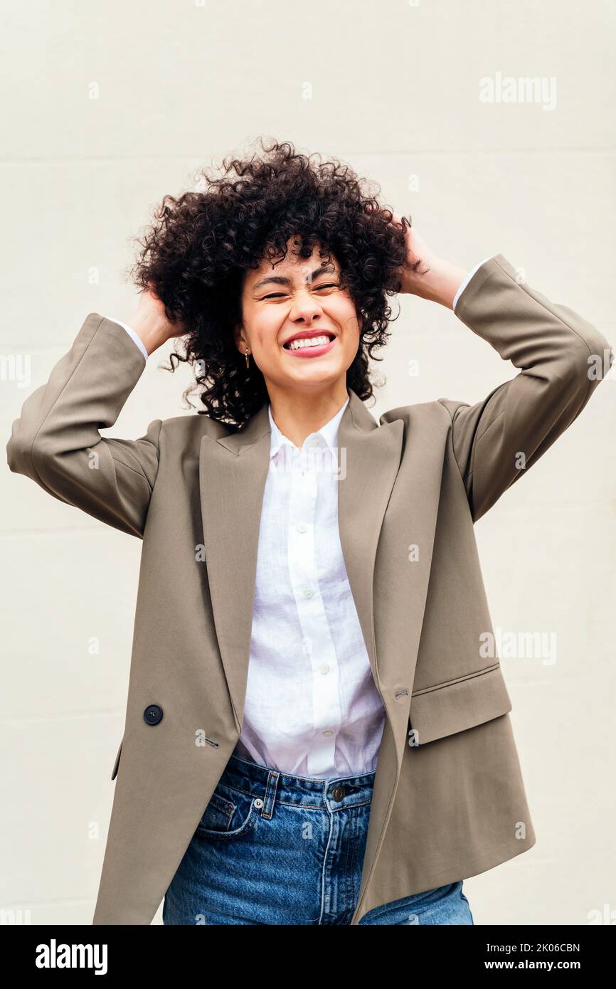 la donna sorride felice scuotendo i capelli ricci Foto Stock