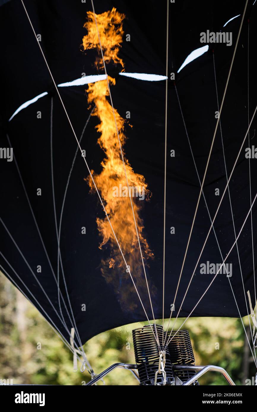 Un uomo utilizza un doppio bruciatore a gas per gonfiare un pallone ad aria calda. Foto Stock