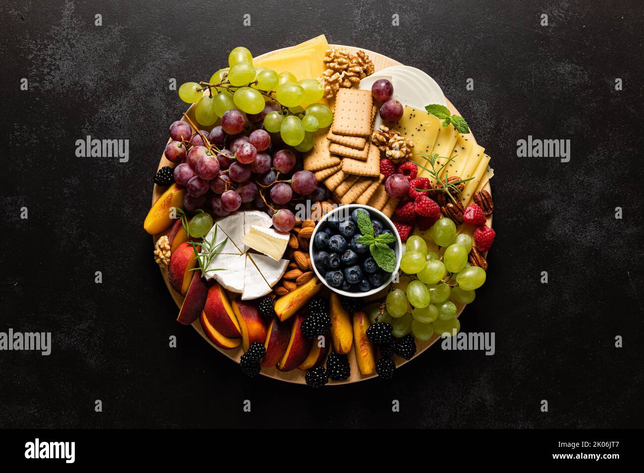 Tagliere di formaggi autunnali con frutta fresca e frutti di bosco serviti con vino bianco, vista dall'alto Foto Stock