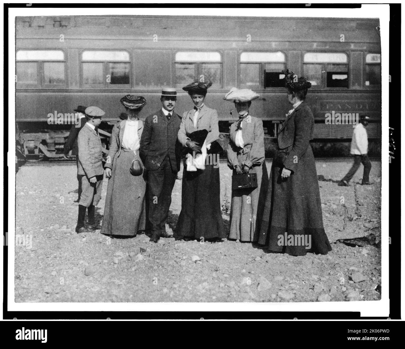 Gruppo di persone posate con auto ferroviaria dietro di loro, Denver, Colorado, (1903?). [Gruppo di persone bianche di fronte a un pullman. Nota portiere afroamericano a destra]. Foto Stock