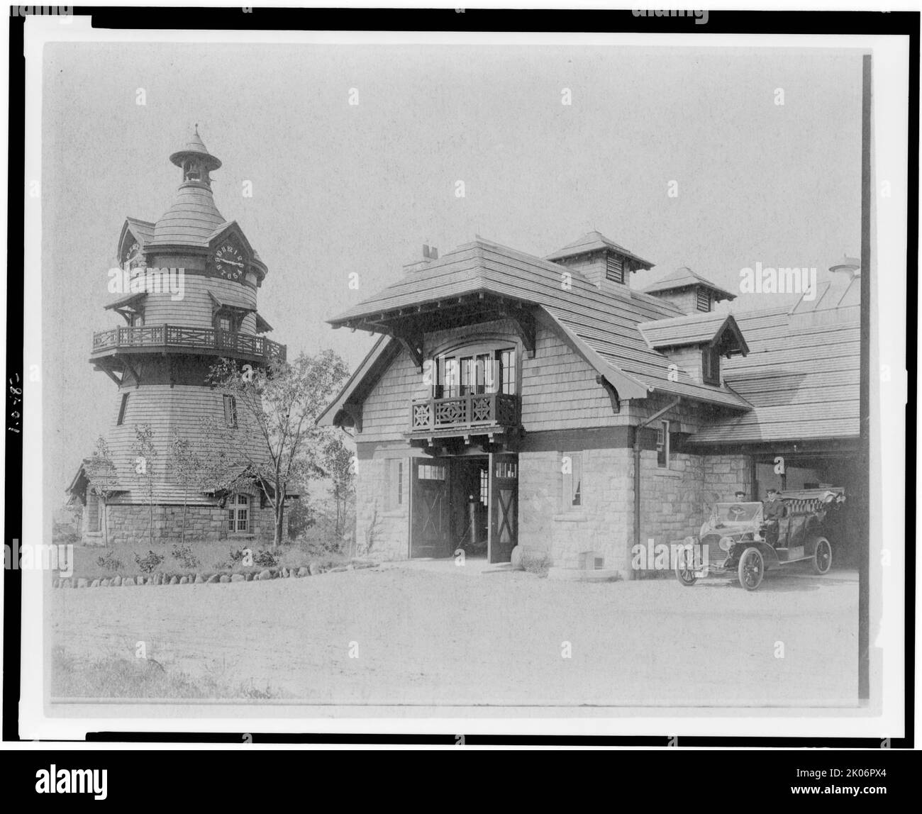 Torre dell'orologio a forma di mulino a vento a sinistra, e parte del garage di Edmund Cogswell Converse, con due uomini in automobile a destra, Greenwich, Connecticut, 1908. La tenuta Conyers Farm, progettata da Donn Barber c1904, era di proprietà dell'imprenditore Edmund C. Converse. Foto Stock