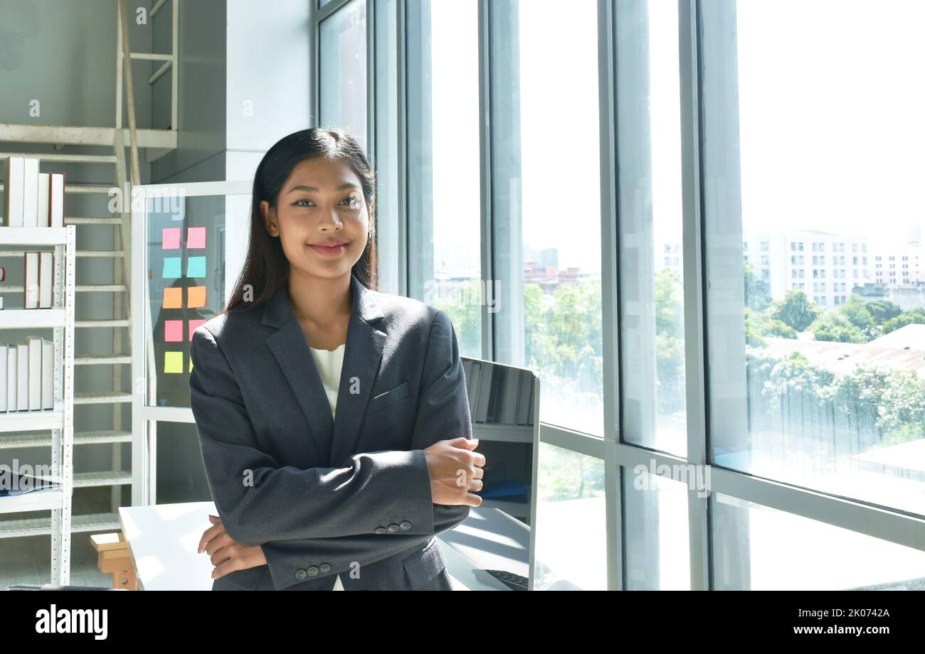 Felice bella donna asiatica busimess posa in vetro sfondo finestra con successo momento in ufficio Foto Stock