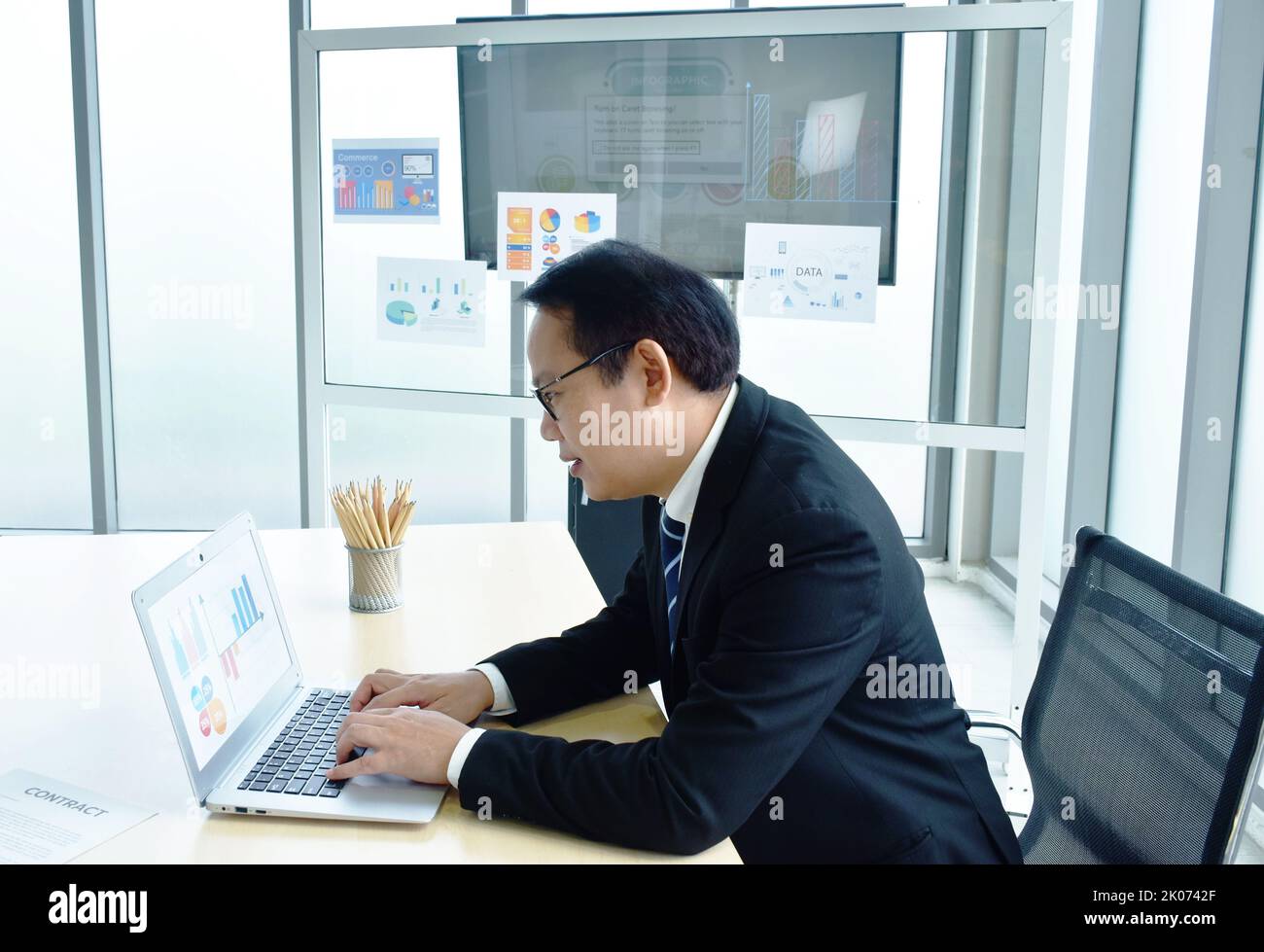 Buon uomo d'affari asiatico che usa un computer portatile in ufficio Foto Stock