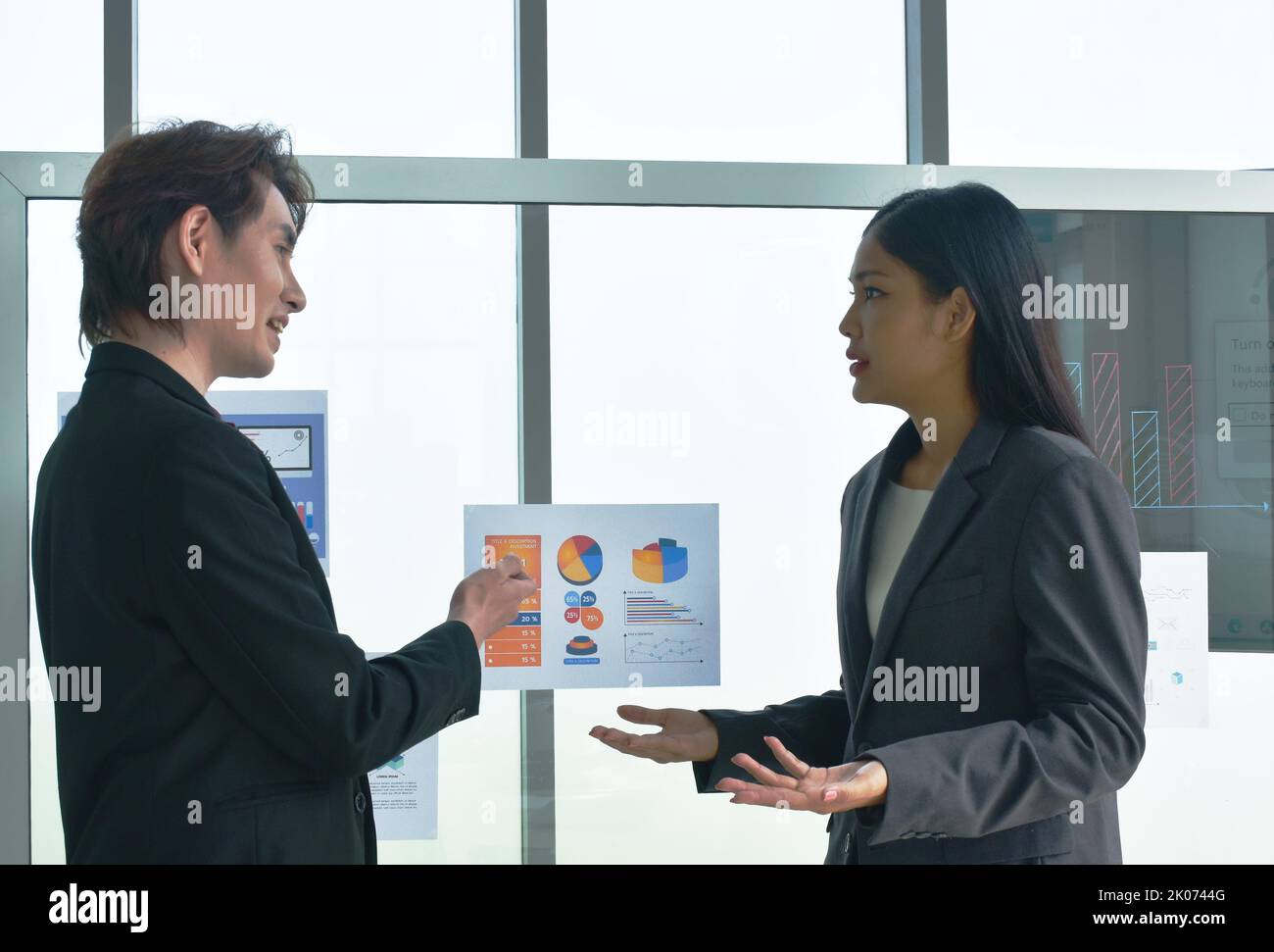 Uomo e donna asiatico di affari che guardano il bastone della nota della carta sul bordo di vetro per discutere e lavorare nell'ufficio Foto Stock