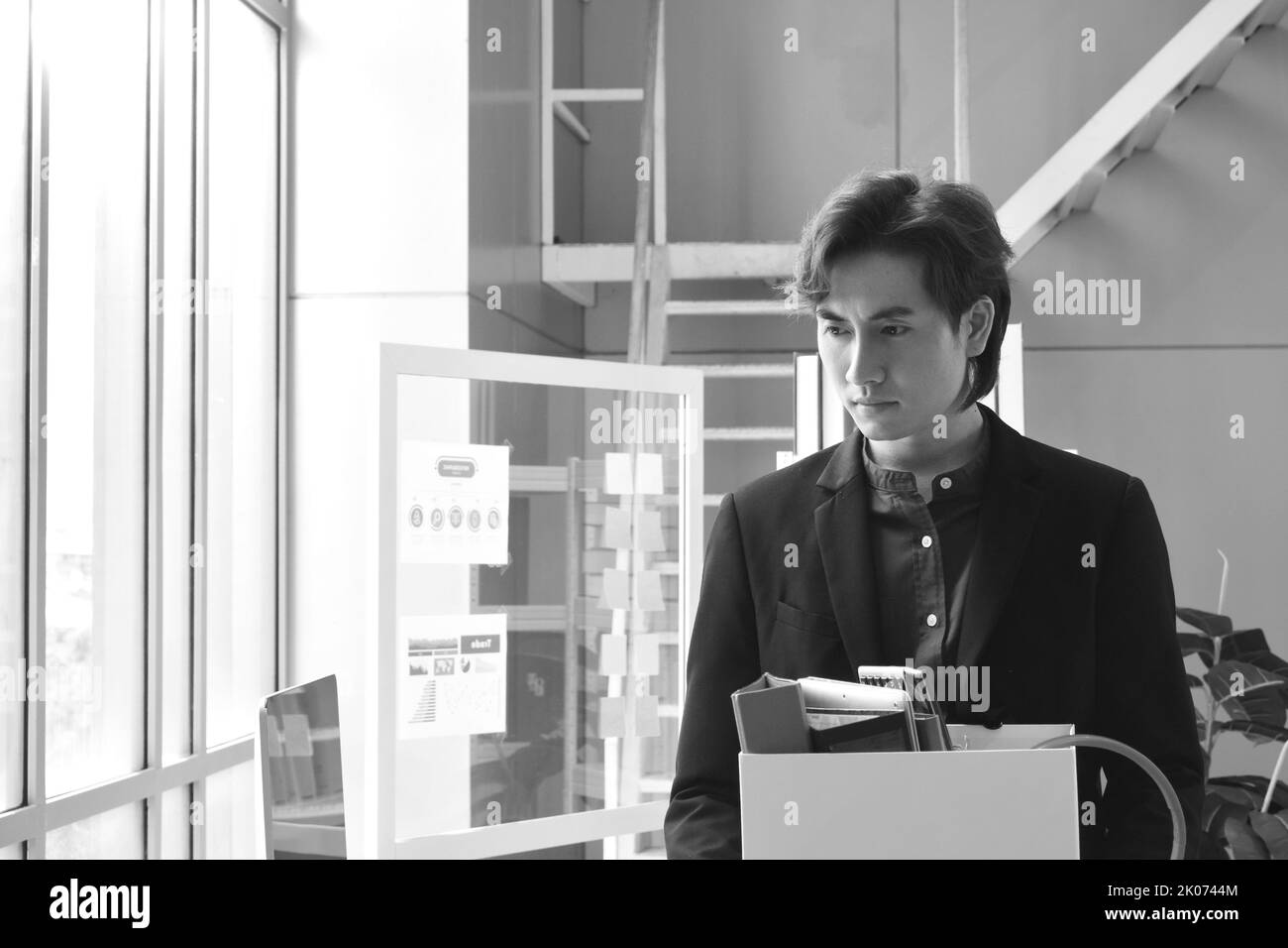 Tristezza uomo asiatico di affari che tiene roba in scatola dopo licenziato fuori e perdita di lavoro in ufficio stanza Foto Stock