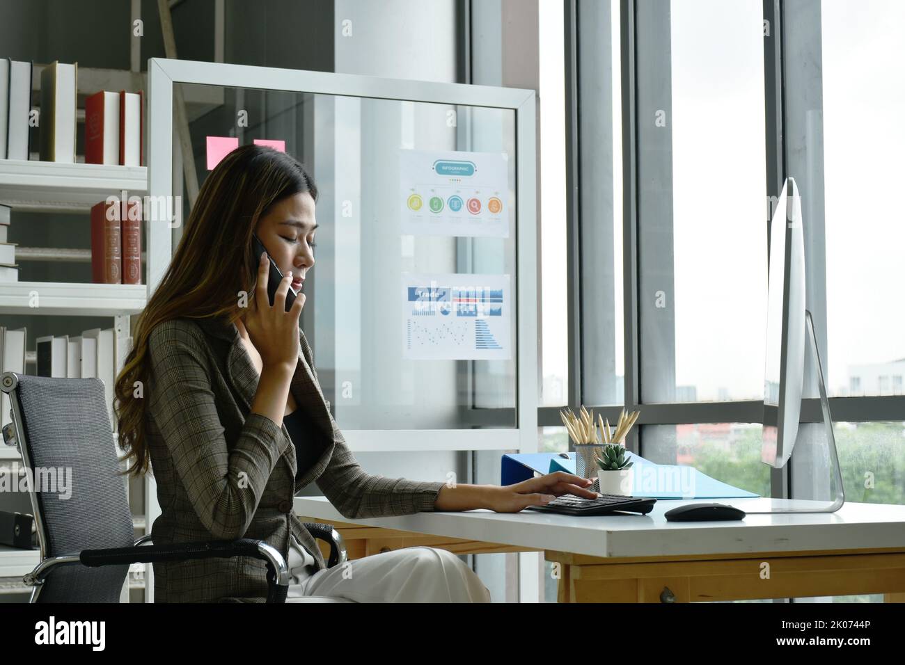 Donna asiatica d'affari che utilizza il telefono cellulare con grave sensazione in ufficio Foto Stock