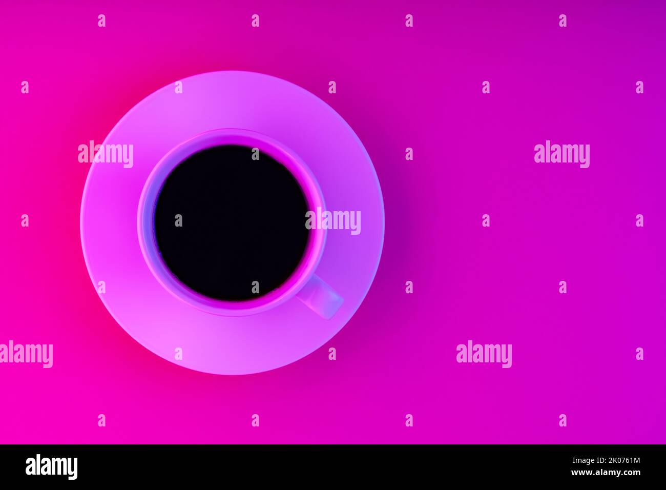Tazza di caffè e piattino con luce al neon rosa. Caffè su sfondo rosa creativo. Vista dall'alto. Spazio di copia Foto Stock