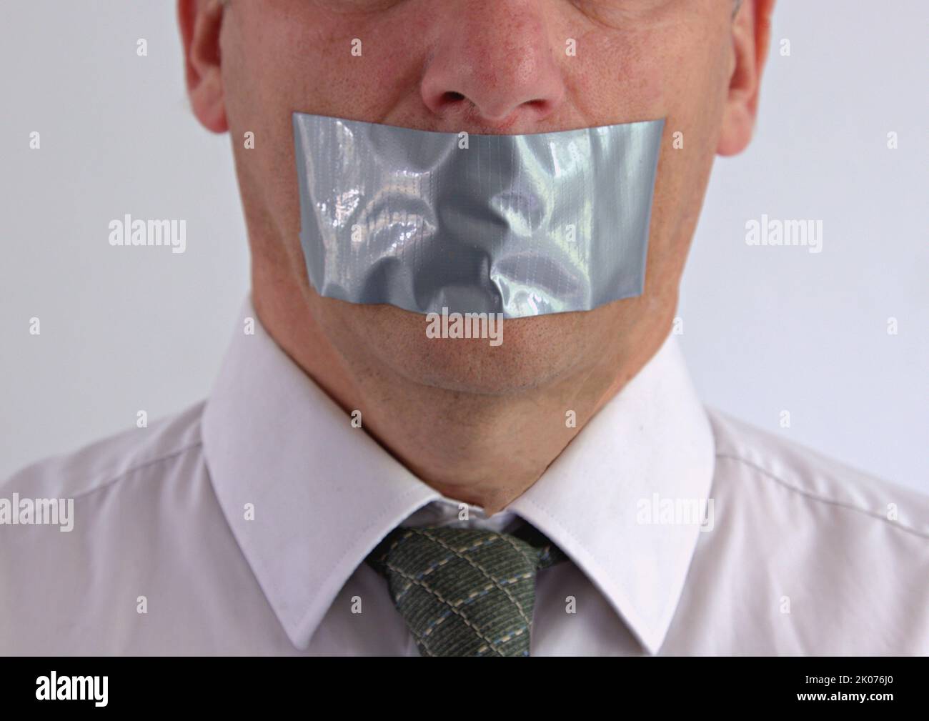 Uomo d'affari che viene messo a tacere con nastro protettivo sopra la bocca Foto Stock