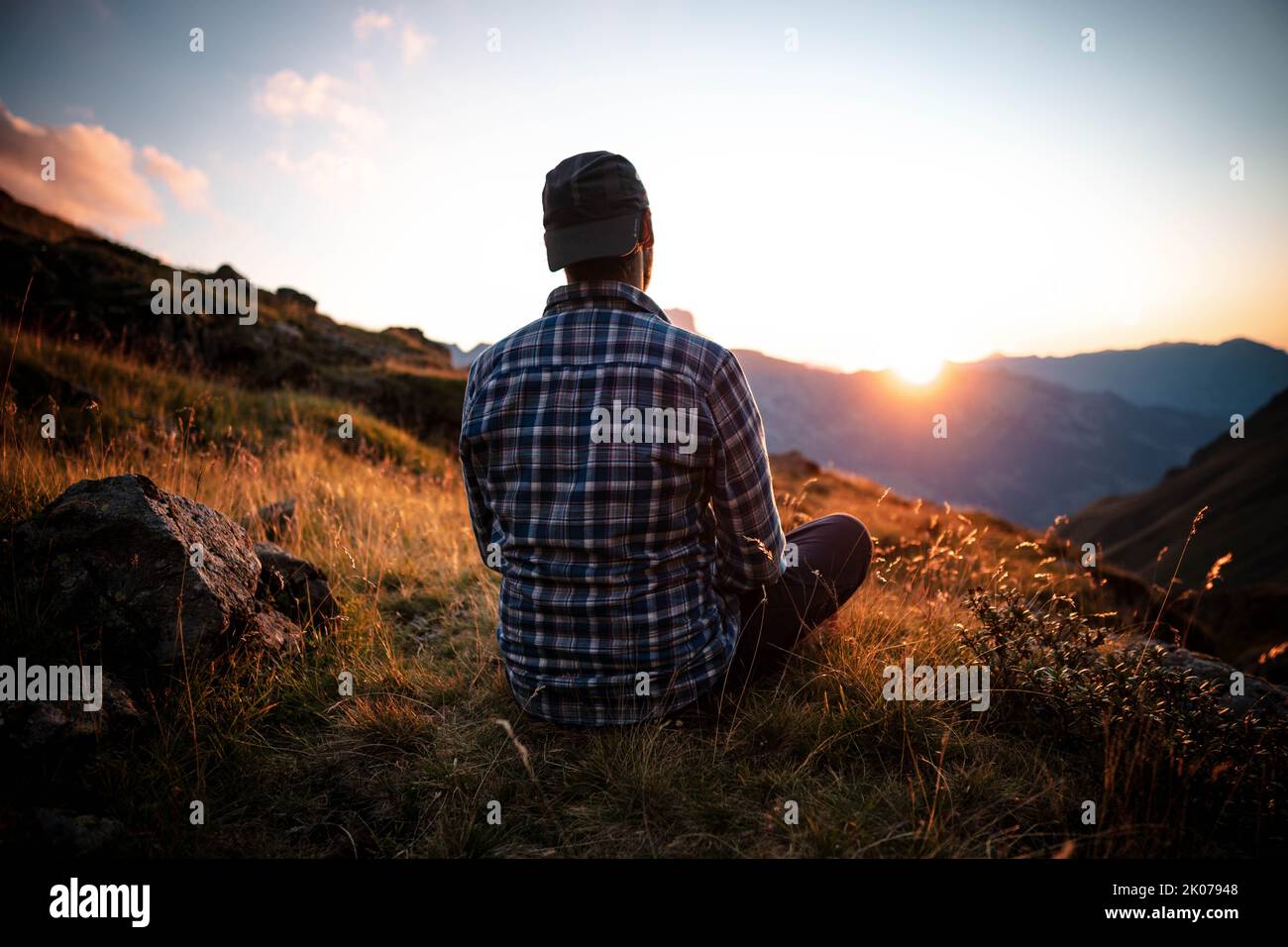 Solitario uomo seduto su una montagna per guardare Sunrise viste da solo, successo e concetto di pace in tono caldo e vintage. Foto Stock