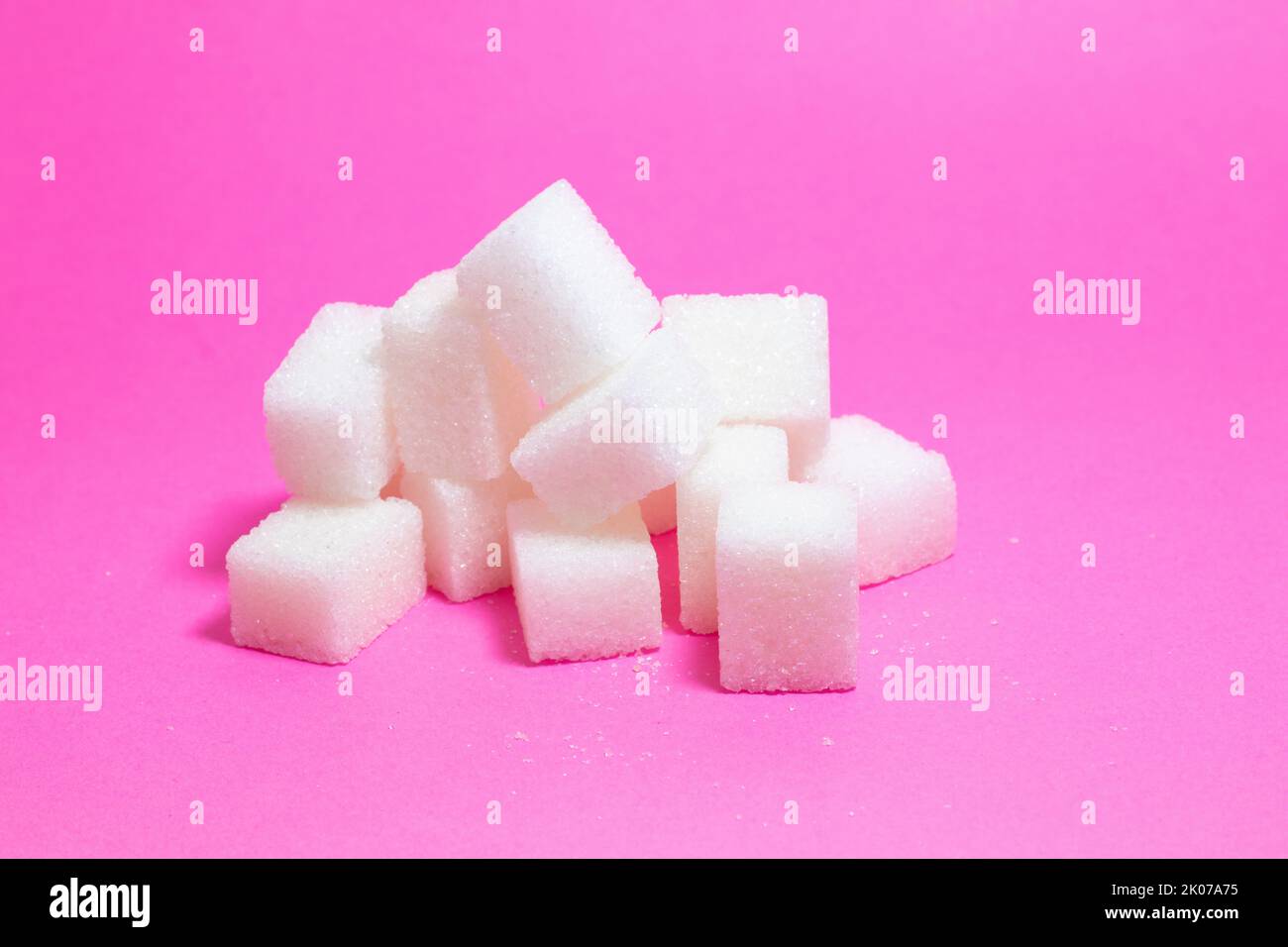 Cubetti di zucchero. Mucchio di cubetti di zucchero isolato su sfondo rosa. Spazio di copia, spazio per il testo. Nessuna gente, nessuno. Concetto di idea alimentare nocivo. Foto Stock