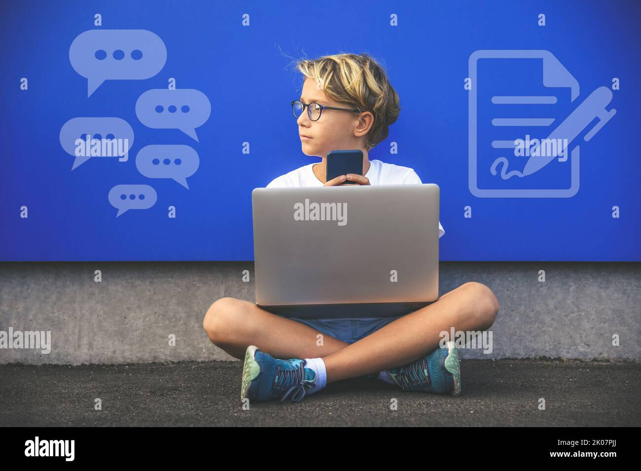 Il ragazzo comunica con il computer portatile e lo smartphone. Tecnologia analogica e digitale. Nuovo concetto tecnologico. Foto Stock