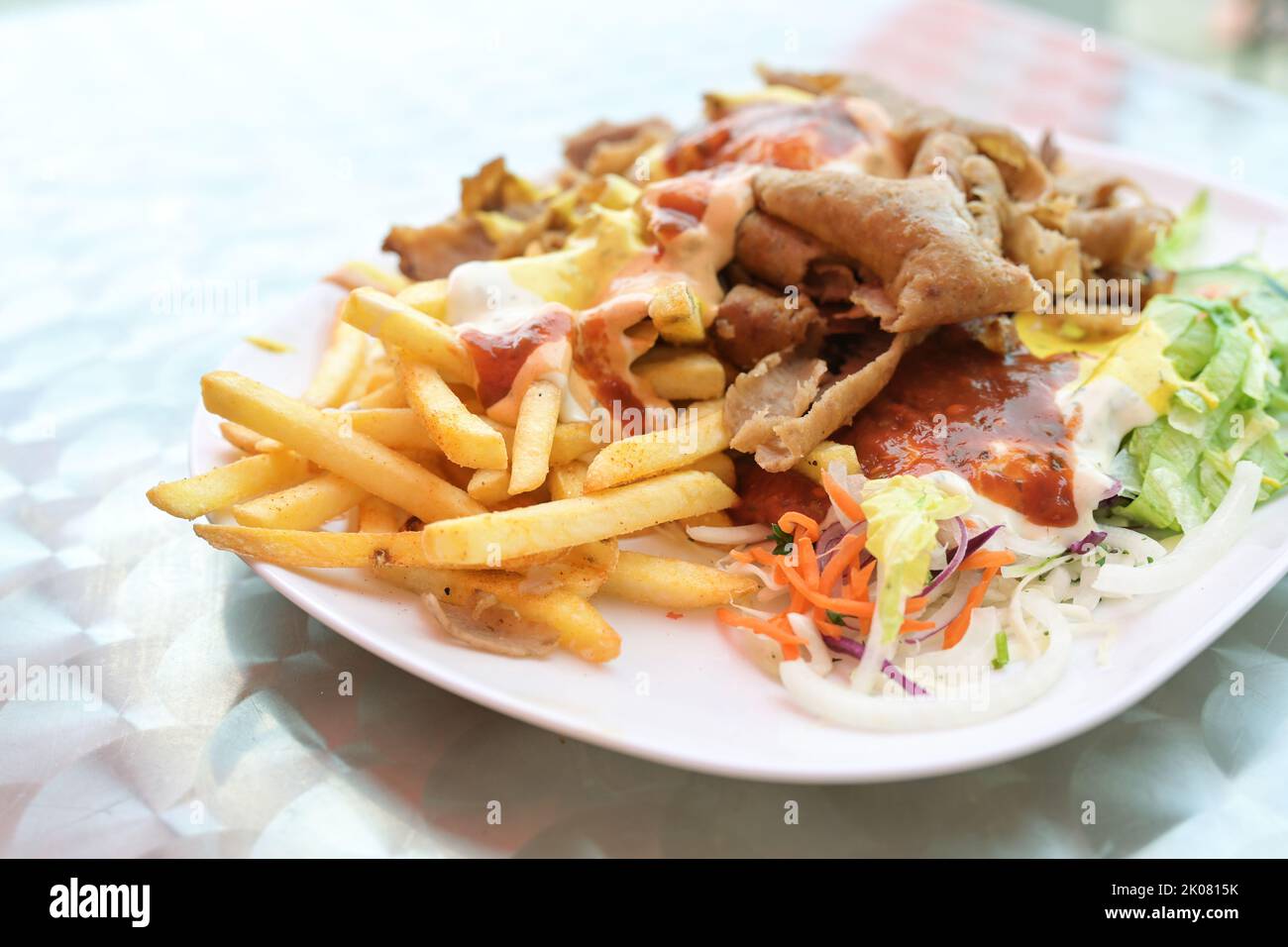 Doner kebab su un piatto con patatine fritte, insalata e salse varie su un piatto, popolare fast food dalla cucina turca, spazio copia, focus selezionato, nar Foto Stock