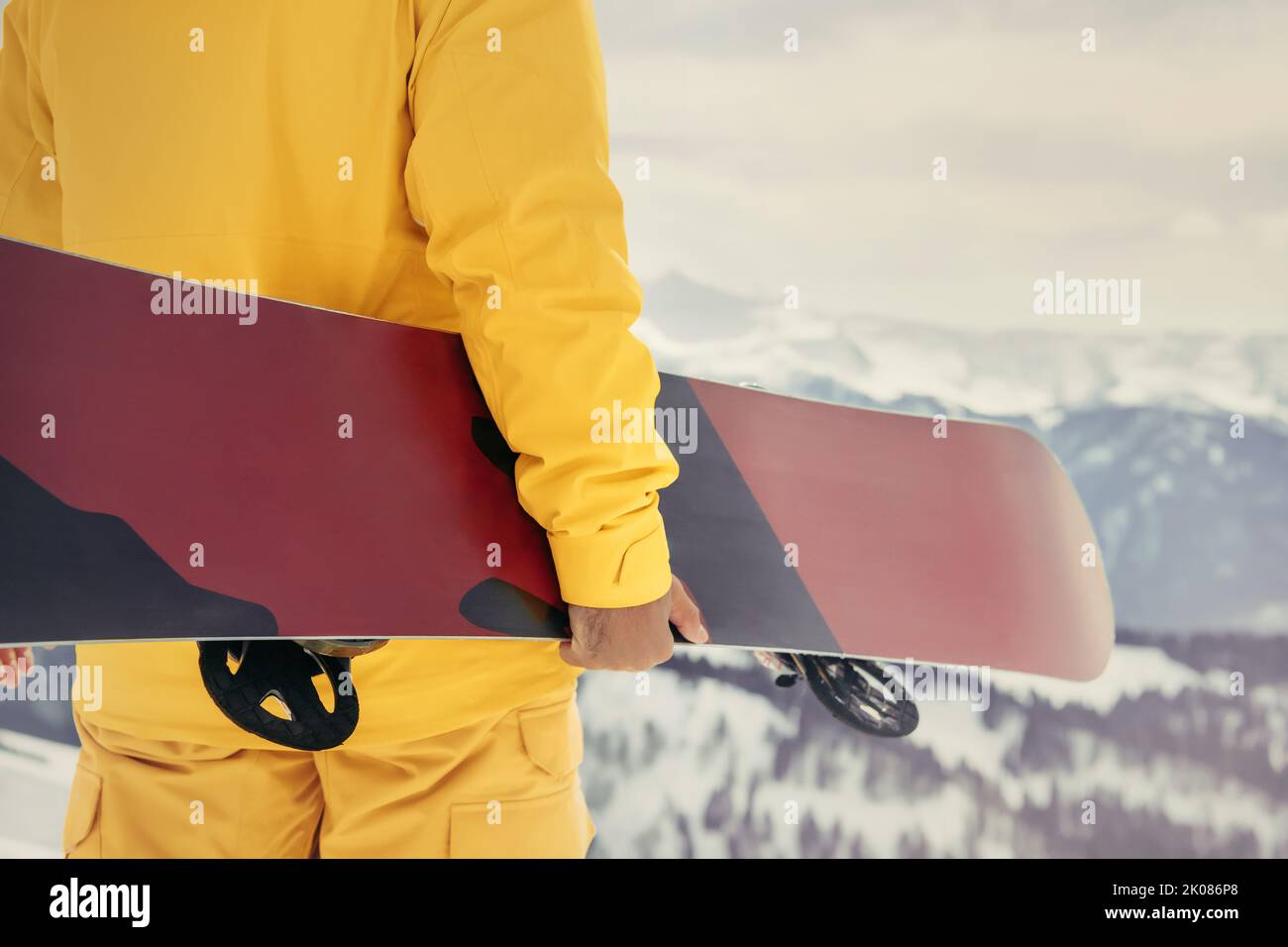 Foto ravvicinata del vero snowboarder in piedi con lo snowboard in mano. Concetto di stazione sciistica Foto Stock