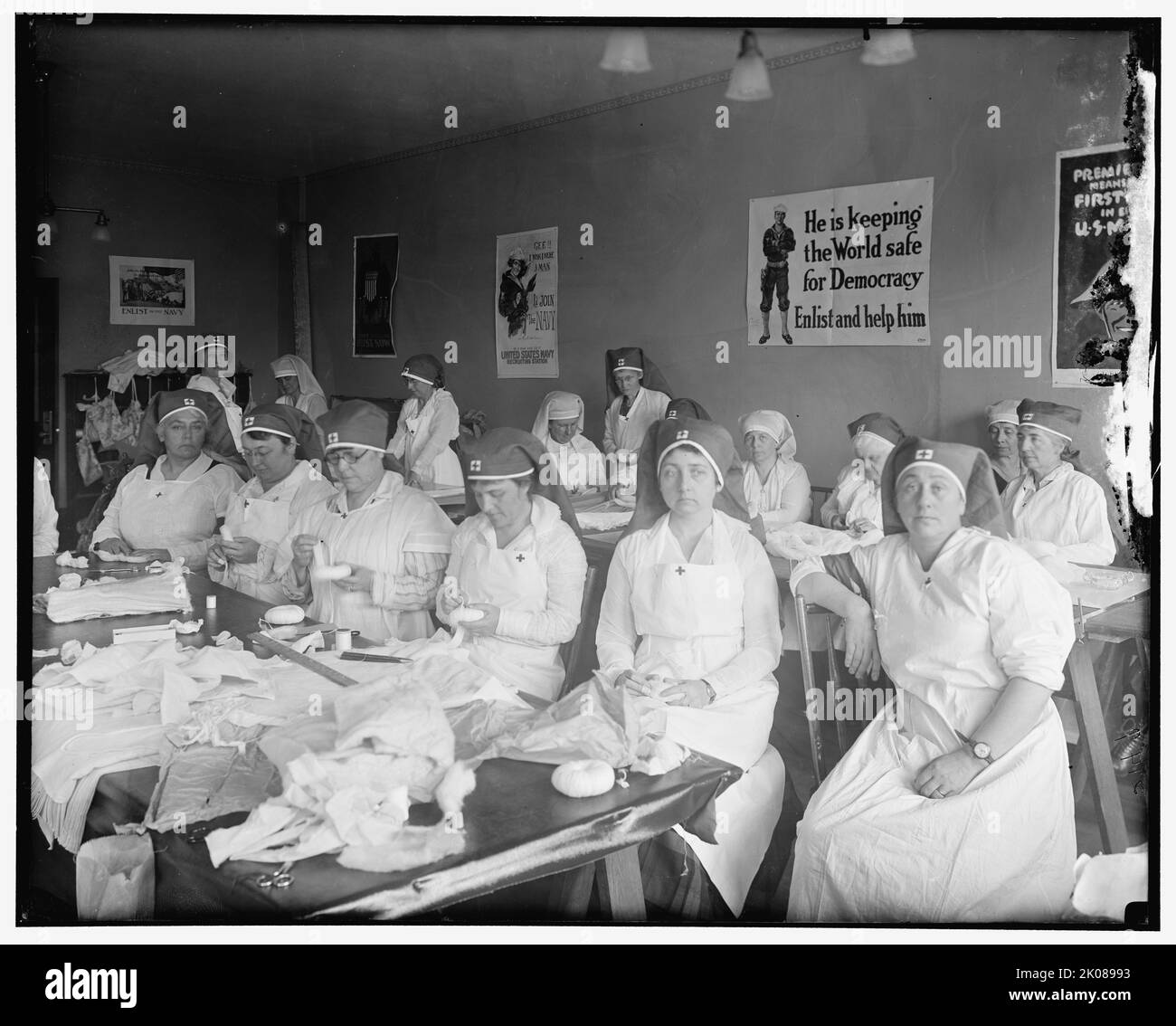 Spogliatoio chirurgico della signora Blair, tra le 1910 e le 1920. Donne in Croce Rossa uniforme preparazione bende. Poster sulla parete leggere: 'Gee!! Vorrei che fossi un uomo - mi unirei alla Marina - essere un uomo e farlo - United States Navy Recruiting Station'; 'sta mantenendo il mondo sicuro per la democrazia - arruolarsi e aiutarlo'. Foto Stock