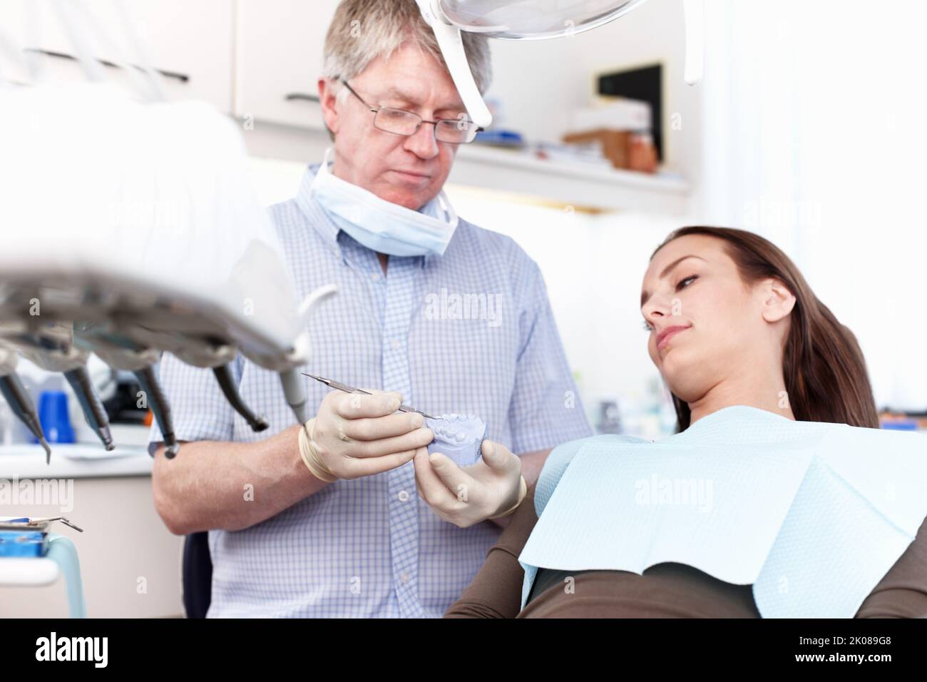 Dentista che tiene falsi denti in clinica. Ritratto di dentista che tiene falsi denti con paziente femmina in clinica. Foto Stock