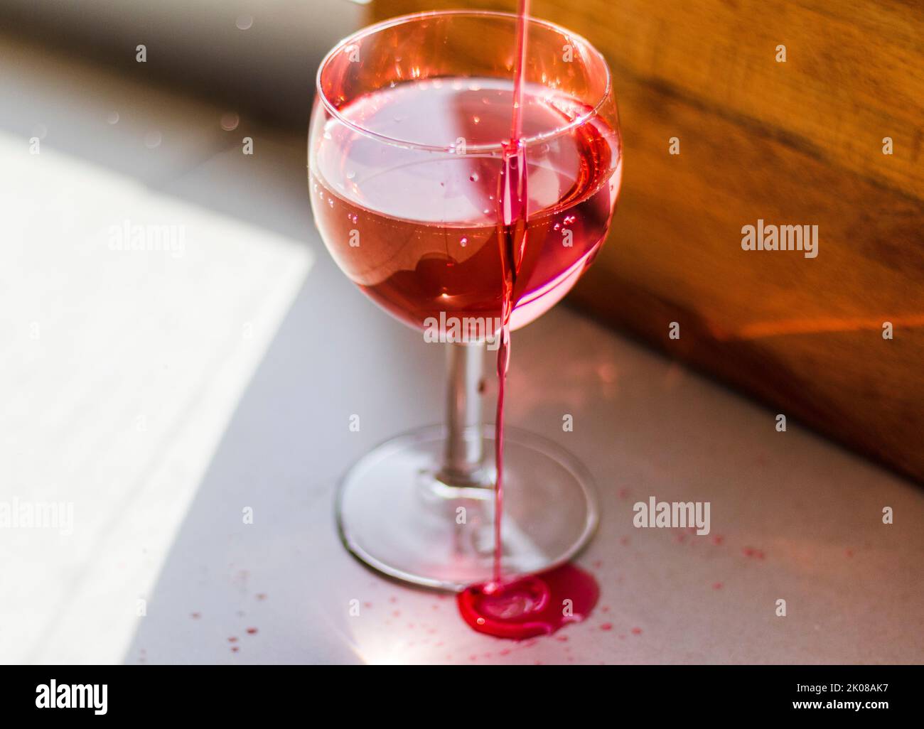 Sparo di un liquido rosso che viene versato nel bicchiere del vino. Foto Stock