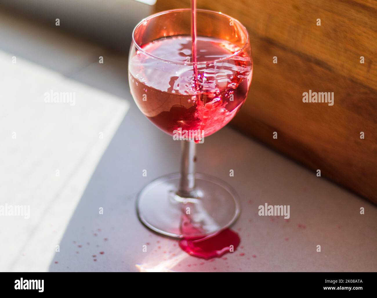 Sparo di un liquido rosso che viene versato nel bicchiere del vino. Foto Stock